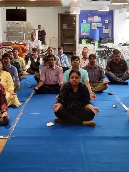 A wide view of a corporate yoga class in progress. We can adapt to any office environment, from a large conference room to a small break area, to create a space for relaxation and rejuvenation.