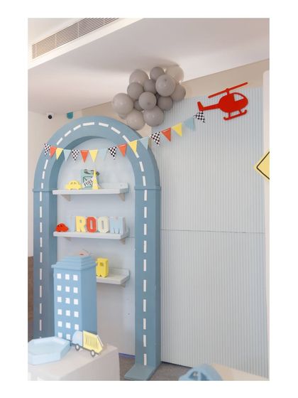A creative shelving unit designed as a road-themed arch, decorated with a helicopter cutout and a mini-pennant banner.