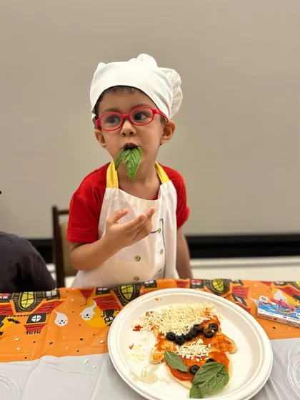 Quality control is very important. This little chef is making sure the basil for his pizza is fresh and tasty before it goes on top.