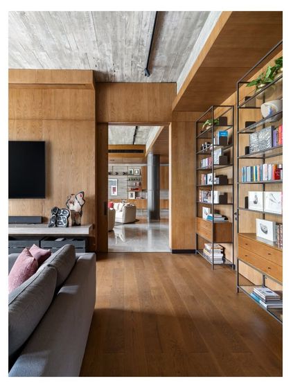 A view from the TV lounge into the main first-floor lounge of the K Residence. The use of consistent wood flooring and paneling creates a sense of architectural continuity, while the different furniture styles give each space its own distinct personality.