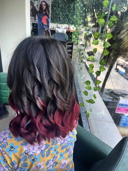 A fun and playful ombré hair color. The tips are dipped in a vibrant red, creating a bold contrast that is perfect for someone looking to make a statement.