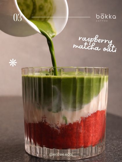 An action shot of matcha being poured into a layered raspberry drink. This dynamic image is visually striking and shows the process of creating a unique beverage. The vibrant colors make it perfect for Instagram.