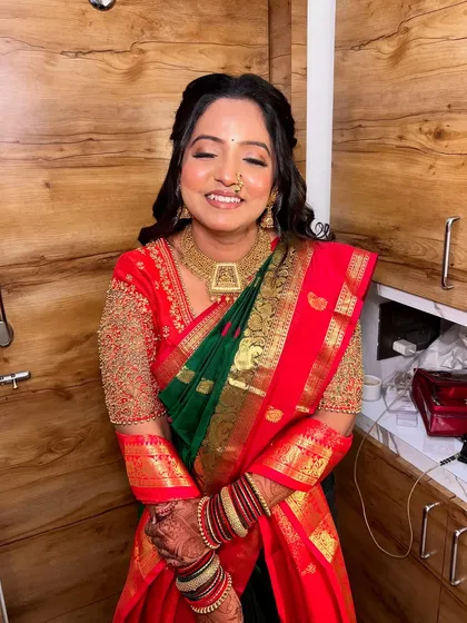 A joyful, eyes-closed shot of a bride ready for her Sakharpuda. The makeup features a radiant glow and soft contouring that enhances her features, perfectly matching the festive spirit of an engagement.