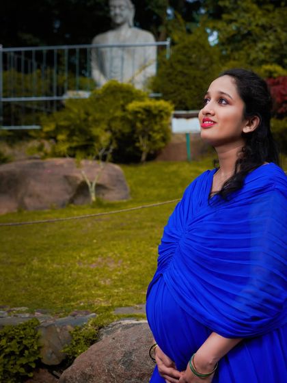 A beautiful solo portrait captured in a park. The rich blue of her dress stands out against the green background, and her upward gaze adds a sense of hope and anticipation.