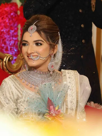A radiant smile from the bride. Her makeup is soft and natural, with a focus on glowing skin and defined eyes that complement her diamond and pink stone jewelry.