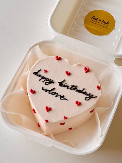 Another view of the pale pink heart-shaped "happy birthday love" bento cake, showcasing its clean lines and simple, heartfelt design.