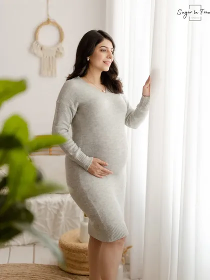 A graceful solo portrait of the mother-to-be looking out the window. The soft knit dress and the bright, airy feel of the shot create a serene and elegant image.