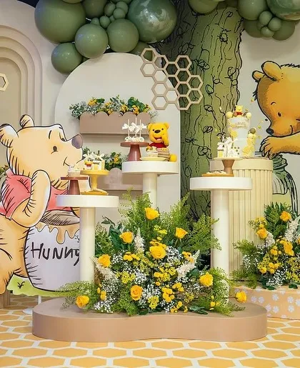 A dessert corner from the Winnie the Pooh baby shower, with "BABY" blocks and a Pooh character cutout next to tiered stands for treats.