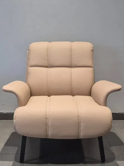 A frontal view of the 'Enigma' lounge chair, showing the clean lines of the tufted backrest and the elegantly curved armrests.