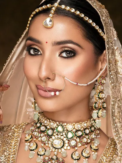 The quintessential bridal portrait, refined. This close-up captures the soft glow of the bride, the intricate details of her polki jewelry, and the delicate veil, all while maintaining a natural and luminous skin finish.