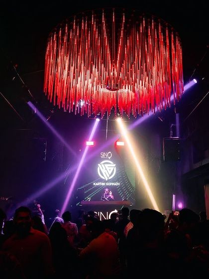 An epic wide shot of the main room at Sinq, Goa, with me on the stage under a massive chandelier.