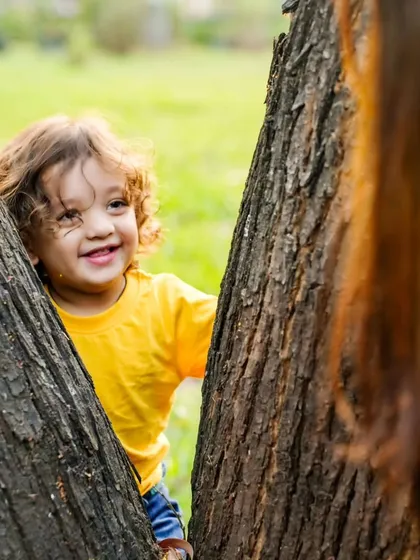 A game of peek-a-boo in the park. I love capturing these playful, candid moments that show a child's true, joyful spirit.