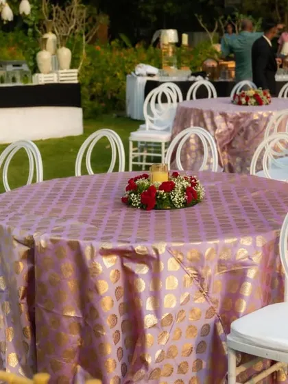 The guest dining tables were elegantly dressed in lavender and gold patterned tablecloths, complete with a simple yet beautiful floral centerpiece. This setup provided a sophisticated space for guests to dine and connect during the celebration.
