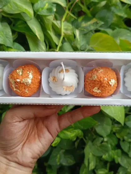 Another angle of the laddoo and modak candle set against a natural green background.