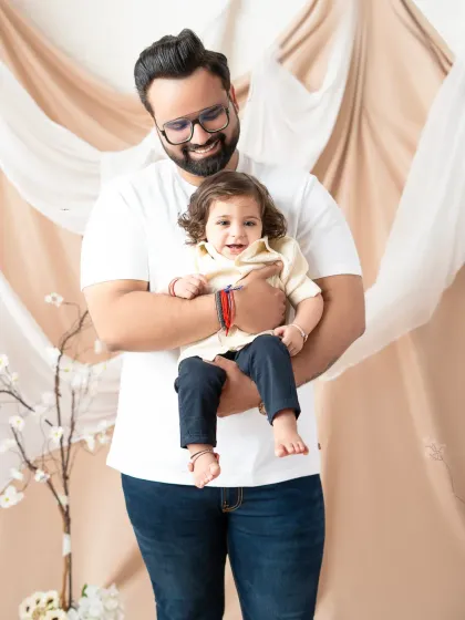 A proud father holds his smiling son. This simple, heartwarming portrait against a neutral studio backdrop perfectly captures the special connection between a dad and his little boy.