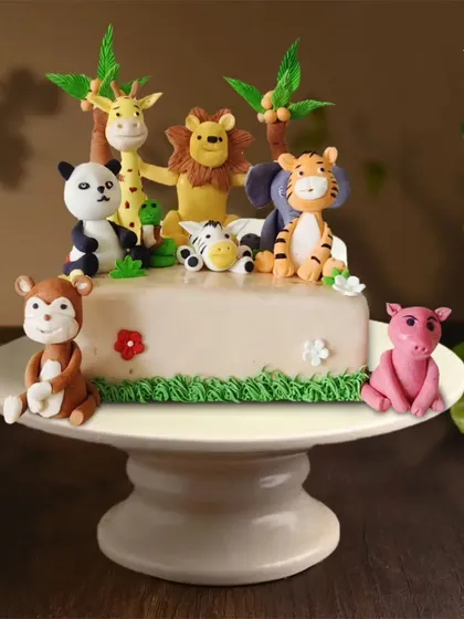 A whole jungle party on one cake. This design features a lion, giraffe, panda, tiger, elephant, monkey, and pig, all handcrafted from fondant for a wild celebration.