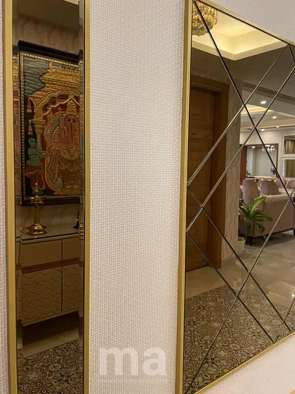 A detail shot of the foyer's accent wall, featuring a large, tinted mirror with a geometric bevelled pattern. The mirror not only adds a decorative touch but also reflects the living space, making the hallway feel wider.