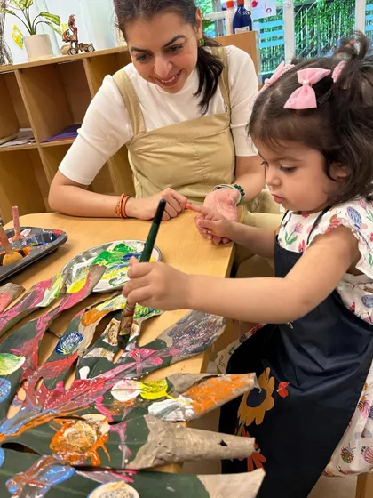 A large monstera leaf becomes a collaborative canvas for parents and children. This intergenerational art project allows for shared creativity, as different hands add layers of color and pattern, transforming a natural object into a collective masterpiece.
