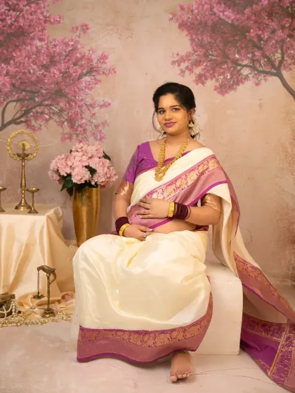 A lovely seated portrait that highlights the mother's peaceful demeanor. The traditional props and the soft pinks of the background create a very feminine and classic maternity photograph.