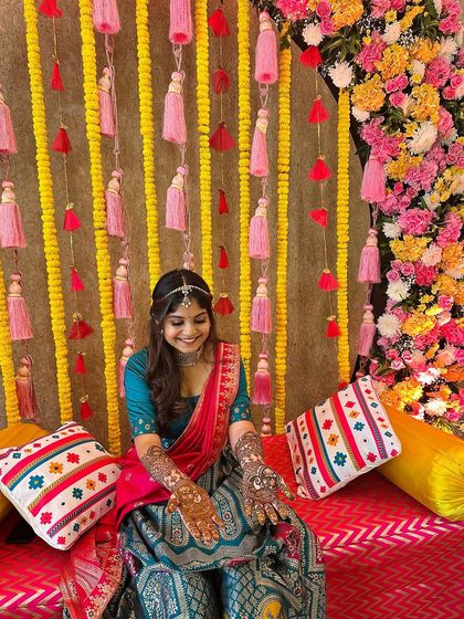 A smiling client at her colorful mehndi ceremony, her hands decorated with my detailed henna patterns.