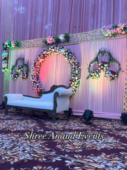 A lovely photo booth or small stage setup with a floral ring and a classic chaise lounge, perfect for guest pictures.