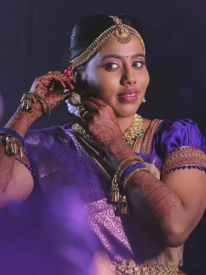 Priya getting ready for her muhurtham. This shot captures the final touches, with her adjusting her earrings, looking like a classic South Indian bride.