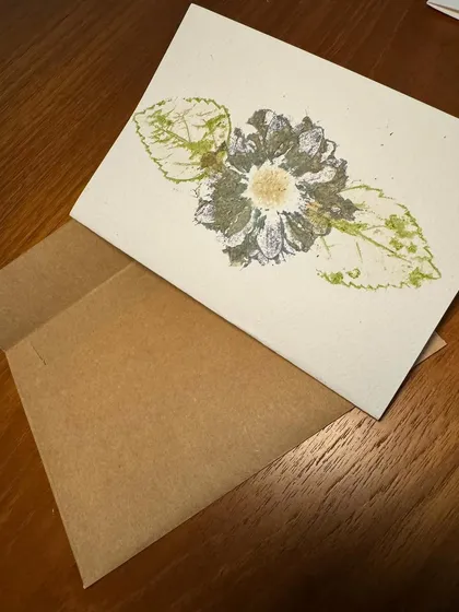 This card showcases the intricate details of a flower and its leaves, a miniature botanical study created with a hammer.