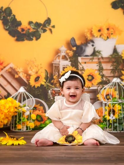 A happy baby girl surrounded by sunflowers. This theme is perfect for a bright, cheerful, and nature-inspired milestone session.