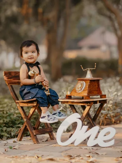 A charming outdoor portrait of a one-year-old boy with a bow tie and a vintage telephone prop.