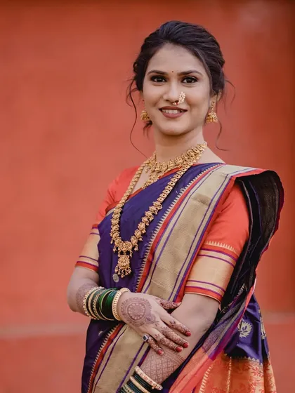 This full-length shot showcases a classic engagement look. The bride wears a traditional silk saree, and her hair is styled in a simple but elegant updo, perfect for the occasion.
