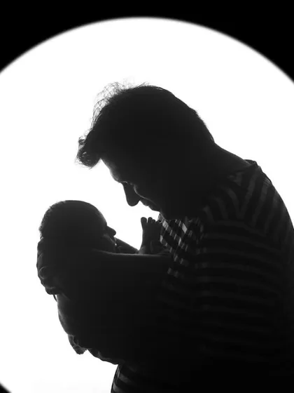 An artistic silhouette of a father and his newborn child. This black and white portrait focuses on the shape and emotion of the moment, creating a powerful and artistic photograph.