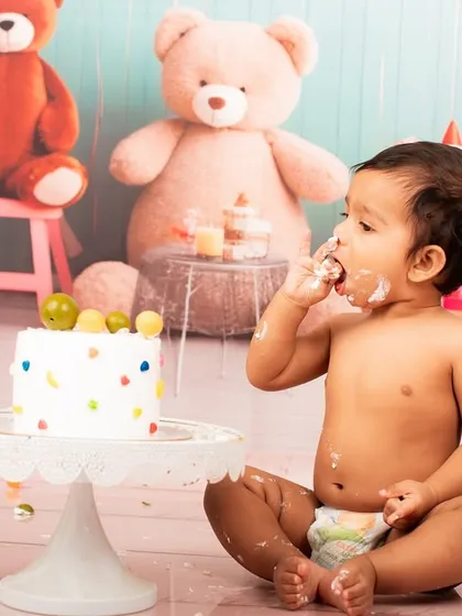 A candid moment from a cake smash photoshoot, capturing the baby's reaction to the sweet treat.