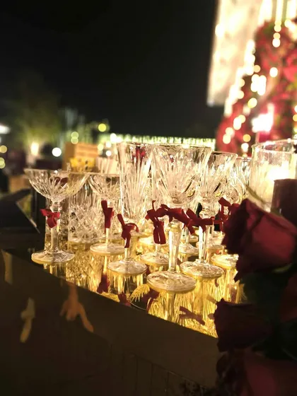 The beauty is in the details. We selected exquisite crystal glassware, each adorned with a small red ribbon, to complement the scarlet and gold theme of this elegant Navjote celebration, ensuring every element felt special.