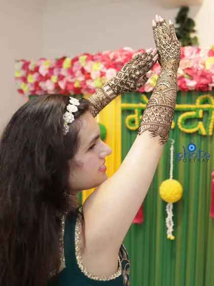 A fun, candid shot of the bride dancing and celebrating during her Mehndi ceremony, showing off her beautiful henna-adorned arms.