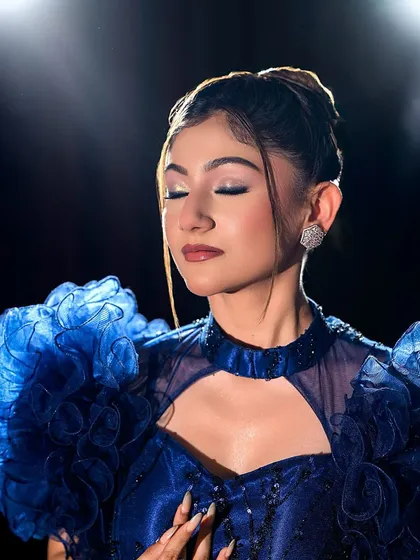 A soft, elegant close-up of the blue gown look with eyes closed.