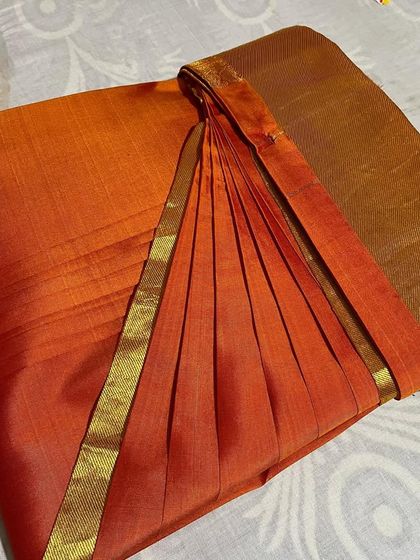An elegant orange saree with a simple gold border, pleated to perfection. This shows that my service is for everyday sarees as well as festive ones.
