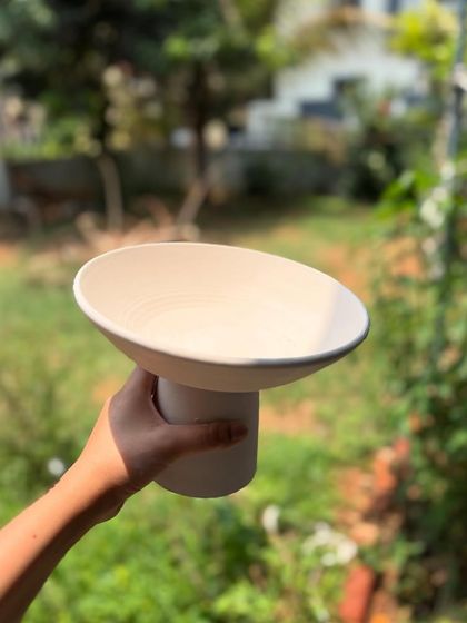An unglazed, or 'bisqued', version of our elevated serving bowl. This is the piece before it gets its color and food-safe coating in the glaze firing.