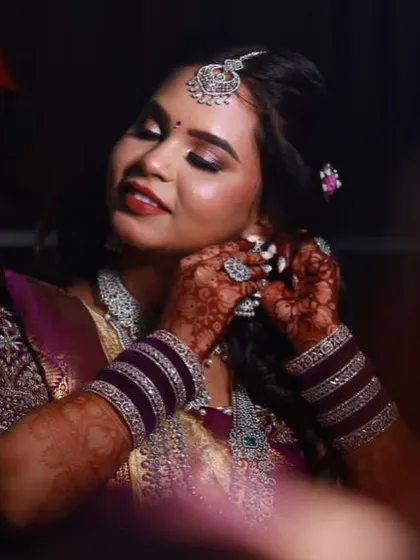 A close-up of the bride getting ready, her beautiful mehendi visible as she puts on her jewelry.