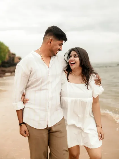 A happy couple walks along the beach, their laughter and a candid moment captured perfectly.