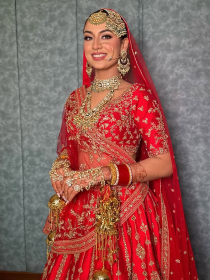 The complete bridal look, showcasing the stunning red lehenga and the makeup that enhances her natural beauty with a radiant glow.