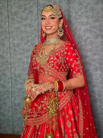 The complete bridal look, showcasing the stunning red lehenga and the makeup that enhances her natural beauty with a radiant glow.