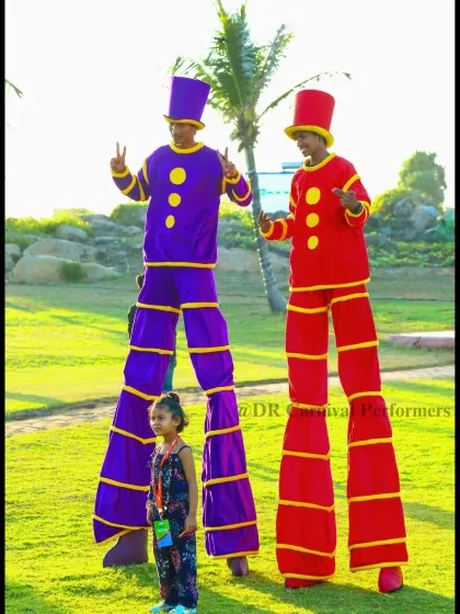 Reaching new heights with every step! Our stilt walkers, dressed in colorful costumes, pose with a young guest, showing how they bring a "wow" factor to any event.