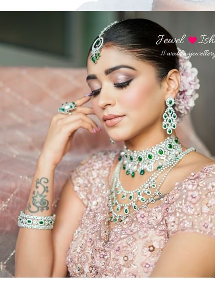 A portrait of modern bridal beauty. The soft makeup and elegant updo allow the emerald and diamond jewellery to truly shine, completing this glamorous look.