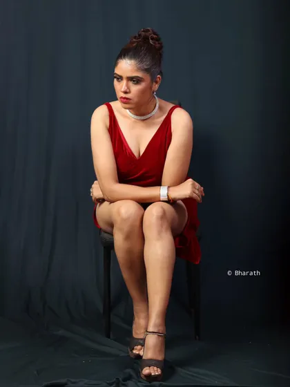 A variation of the seated pose, conveying a more pensive mood. The lighting sculpts the model's features and the texture of the velvet dress.