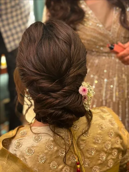 A twisted and textured bun with a single pink flower for a touch of softness. This is a versatile updo that works beautifully for bridesmaids or for a pre-wedding event.