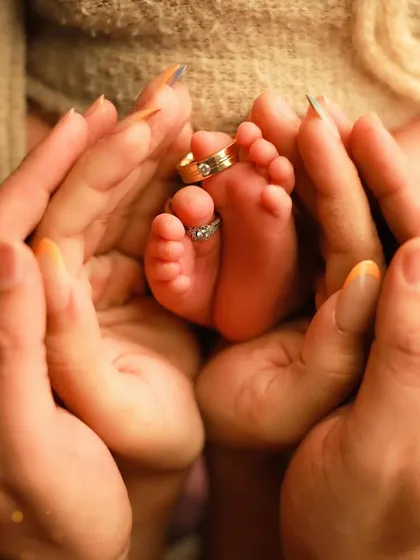 It's all about the tiny details. We love creating shots that show the scale of how small your baby is, like this image of parents' hands cradling their newborn's feet, with their wedding rings slipped onto the toes. It’s a powerful symbol of family and love.