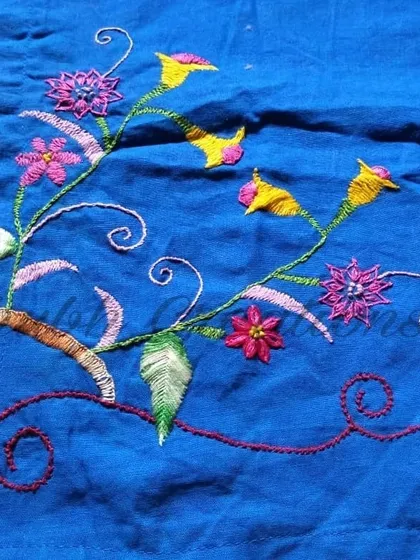 A vibrant floral vine embroidered onto a bright blue fabric. This piece showcases how different stitches, like the satin stitch for flowers and stem stitch for vines, can be combined to create a dynamic design.