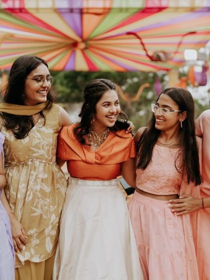 The bride sharing a laugh with her bridesmaids at a colorful carnival-themed party.