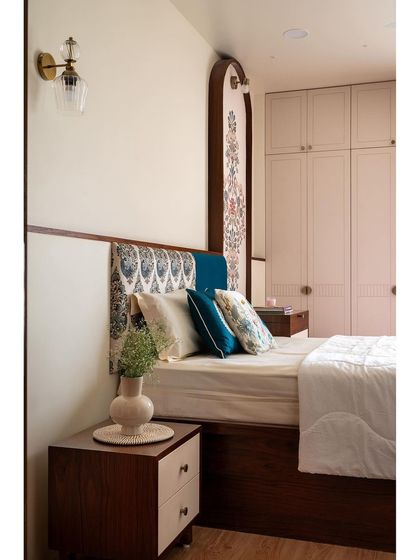 This master bedroom combines a contemporary pink wardrobe with more traditional elements, like the custom-made mural in an arched frame and the patterned fabric on the headboard.