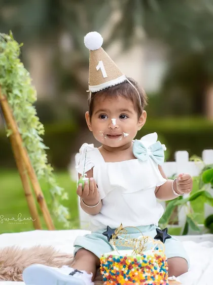 A sweet moment from an outdoor first birthday cake smash. The soft light and natural setting create a beautiful, relaxed atmosphere for celebrating.